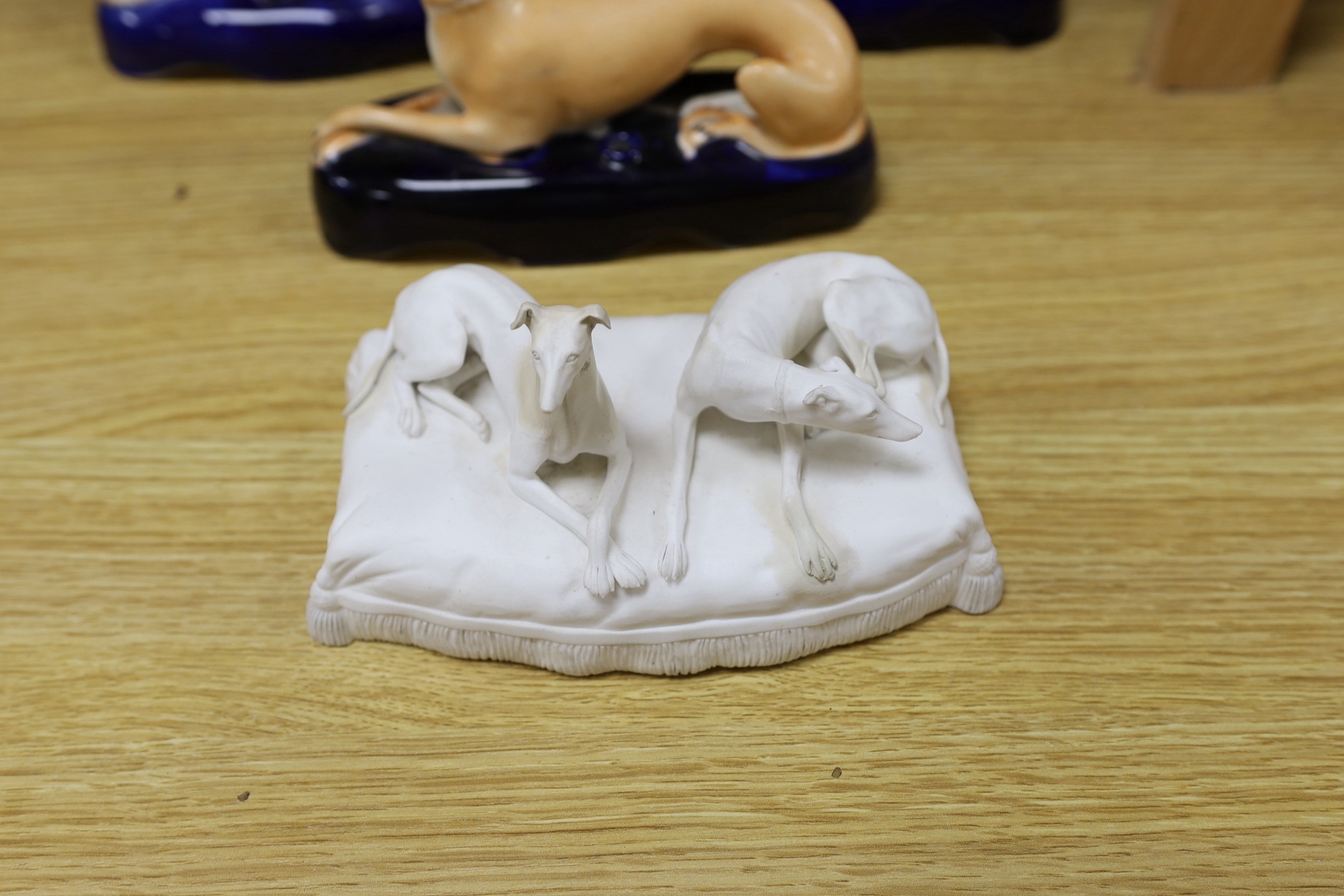 A Staffordshire pottery figure of John Wesley, six Staffordshire pottery models of hounds, and a white bisque group of two hounds on a cushion, tallest 29cm, (8)